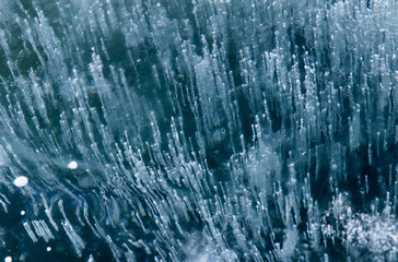 Frozen Baikal lake with cracks and methane bubbles on the transparent ice surface. Winter abstract and blue ice background.