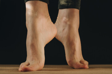 Front view low key close up of woman bare feet on ballerina tip toes on a cork mat and a black...