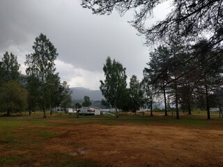 small camping grounds with clouds and a lake in the background