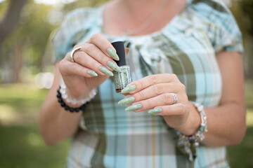 Female hands with long nails with light green mint nail polish