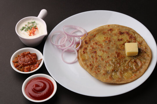 Traditional Indian food Aloo paratha or potato stuffed flat bread. served with pickle  tomato ketchup and curd, butter, onion.