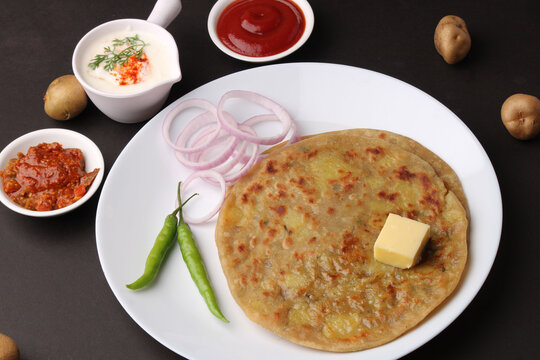 Traditional Indian food Aloo paratha or potato stuffed flat bread. served with pickle  tomato ketchup and curd, butter, onion, chili.