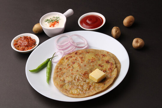 Traditional Indian food Aloo paratha or potato stuffed flat bread. served with pickle  tomato ketchup and curd, butter, onion, chili.