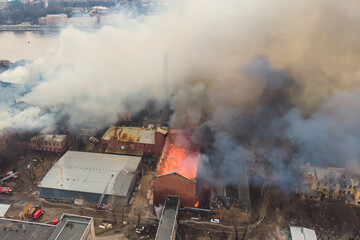 Massive large blaze fire in the city, aerial drone top view brick factory building on fire, hell...