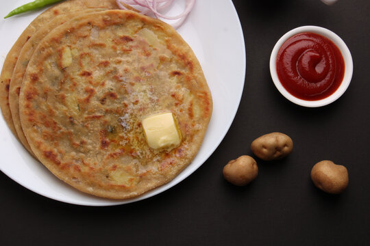 Traditional Indian food Aloo paratha or potato stuffed flat bread. served with pickle  tomato ketchup and curd, butter, onion, chili.