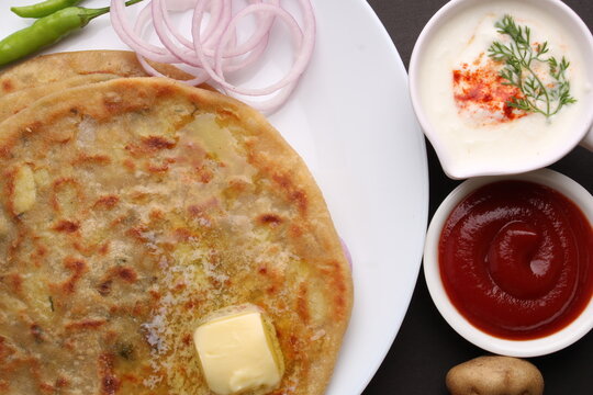 Traditional Indian food Aloo paratha or potato stuffed flat bread. served with pickle  tomato ketchup and curd, butter, onion, chili.