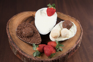 Chocolate Easter Eggs filled with brigadeiro (brigadier), powdered milk and strawberries. Goumert egg chocolate tradition in Brazil. Wood Background