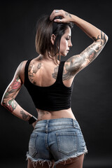 Bellissima ragazza mora con i tatuaggi su tutto il corpo, posa seria isolata su sfondo nero