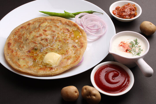 Traditional Indian food Aloo paratha or potato stuffed flat bread. served with pickle  tomato ketchup and curd, butter, onion, chili.