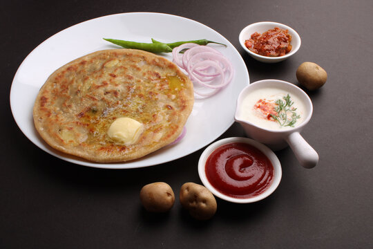 Traditional Indian food Aloo paratha or potato stuffed flat bread. served with pickle  tomato ketchup and curd, butter, onion, chili.
