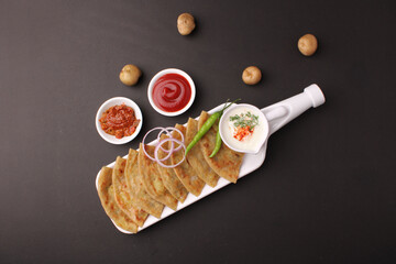 Traditional Indian food Aloo paratha or potato stuffed flat bread. served with pickle  tomato ketchup and curd, butter, onion chili.
