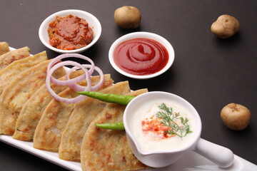 Traditional Indian food Aloo paratha or potato stuffed flat bread. served with pickle  tomato ketchup and curd, butter, onion chili.