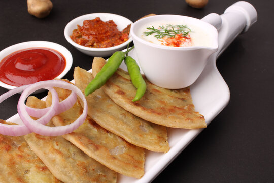 Traditional Indian food Aloo paratha or potato stuffed flat bread. served with pickle  tomato ketchup and curd, butter, onion chili.