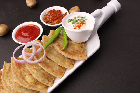 Traditional Indian food Aloo paratha or potato stuffed flat bread. served with pickle  tomato ketchup and curd, butter, onion chili.