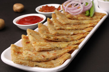 Traditional Indian food Aloo paratha or potato stuffed flat bread. served with pickle  tomato ketchup and curd, butter, onion chili.