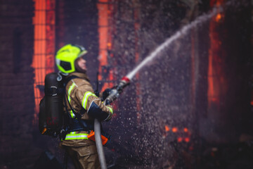 Firefighters put out large massive fire blaze, group of fire men in uniform during fire fighting operation in the city streets, firefighters with the fire engine truck fighting vehicle