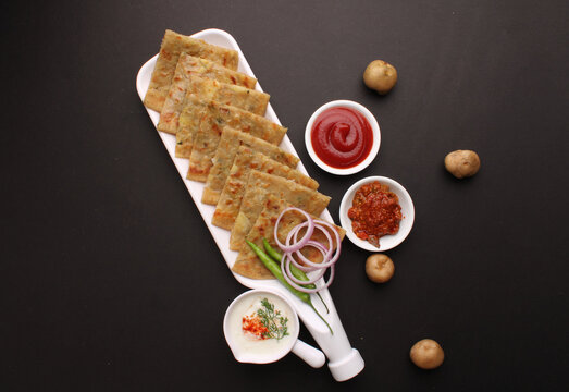 Traditional Indian food Aloo paratha or potato stuffed flat bread. served with pickle  tomato ketchup and curd, butter, onion chili.