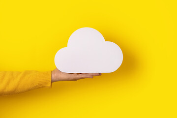 Cloud computing concept, hand holding cloud over yellow background, cloud storage