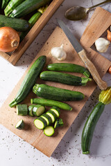 Fresh green zucchini on wooden board with knife. Top view.