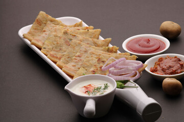 Traditional Indian food Aloo paratha or potato stuffed flat bread. served with pickle  tomato ketchup and curd, butter, onion chili.