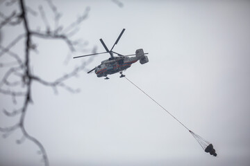 Fire fighting helicopter silhouette with bambi bucket for сarrying water to put out a massive...