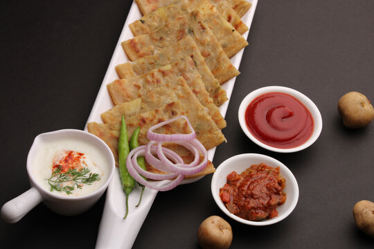 Traditional Indian food Aloo paratha or potato stuffed flat bread. served with pickle  tomato ketchup and curd, butter, onion chili.
