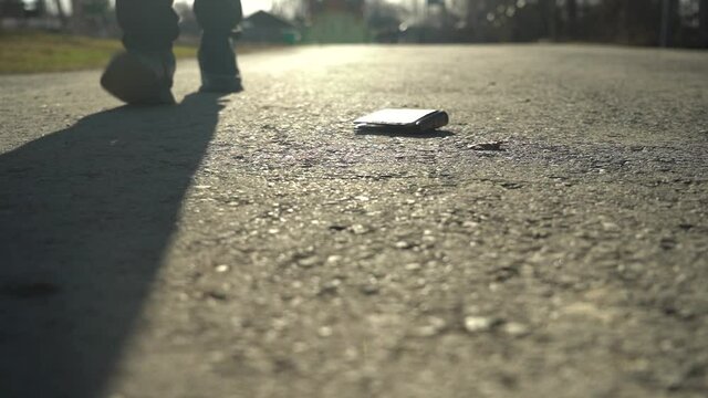 The man picks up the wallet from the sidewalk. The concept of carelessness and loss of money