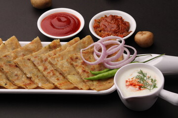 Traditional Indian food Aloo paratha or potato stuffed flat bread. served with pickle  tomato ketchup and curd, butter, onion chili.