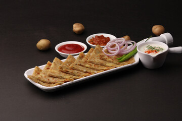 Fototapeta na wymiar Traditional Indian food Aloo paratha or potato stuffed flat bread. served with pickle tomato ketchup and curd, butter, onion chili.