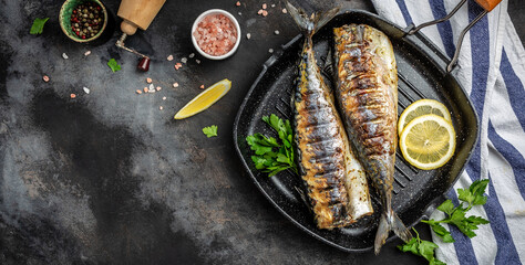 Grilled mackerel fish in a pan with lemon herbs and spices, Long banner format, top view