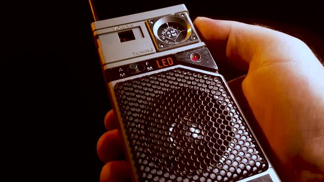 Searching for AM frequency radio station on portable transistor receiver, close up