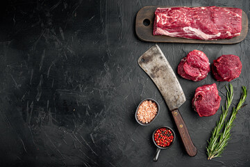 Fresh Raw Beef steak Mignon whole cut , with old butcher cleaver knife, on black stone background, top view flat lay, with copy space for text