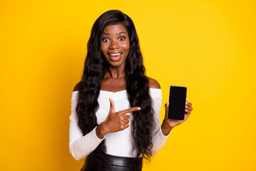 Naklejka premium Photo portrait of girl with long hair showing cellphone display with copyspace isolated bright yellow color background