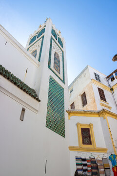 Minaret of the Grand Mosque of Tangier against the blue sky and historical houses in the medina of Tangier, Morocco