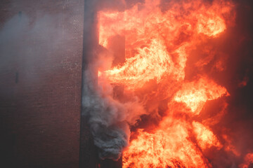 Massive large blaze fire in the city, brick factory building on fire, hell major fire explosion flame blast,  with firefighters team firemen on duty, arson, burning house damage destruction