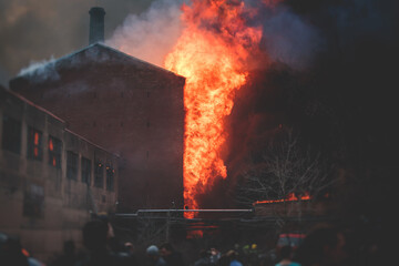 Massive large blaze fire in the city, brick factory building on fire, hell major fire explosion flame blast,  with firefighters team firemen on duty, arson, burning house damage destruction