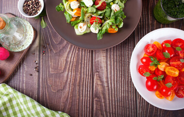 salads of fresh cherry tomatoes, mozzarella, basil and other greens on the dinner table