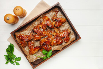 Chicken wings grill in teriyaki sauce with sesame in a wooden tray on a bright background. Top View
