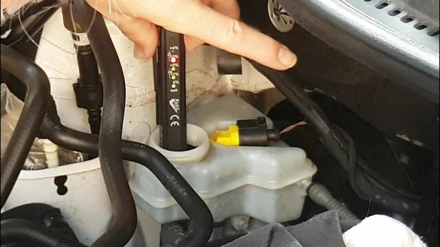 Showing how to use a brake fluid tester on a car. Incl result = red light on to show fluid needs changing.