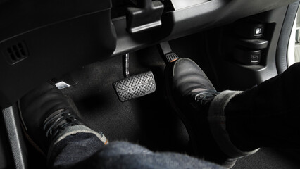 Close up the foot pressing foot pedal of a car to drive. Accelerator and brake pedal in a car. Driver driving the car by pushing accelerator and break pedals of the car. inside vehicle. control pedal. - obrazy, fototapety, plakaty