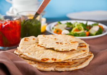 Homemade Indian naan flatbread with fresh salad and dips on the dinner table.