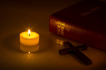 Candle , Bible and cross on the table. Cross and Holly bible in the dark under candlelight .