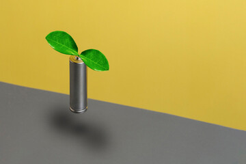 Levitation alkaline rechargeable battery with green leaf against trendy color yellow and grey...