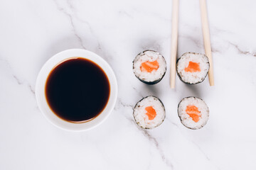 Classic sashimi with salmon fish, soy sauce and chopsticks on white marble table background - maki sushi roll, nori maki, futomaki. Asian food delivery, sushi bar menu, online home order food concept