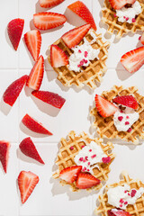 waffles with strawberries on a white tiled background