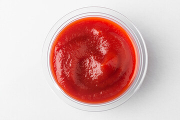 Small cup of tomato sauce, top view on white background