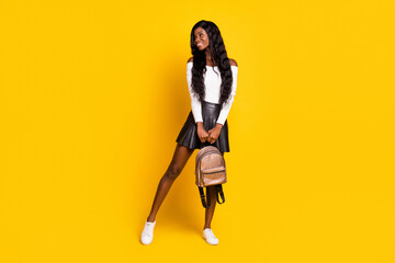 Full length body size photo black skinned brunette smiling looking blank space keeping backpack isolated on vivid yellow color background