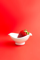strawberry in bowl on red background. Copy space.