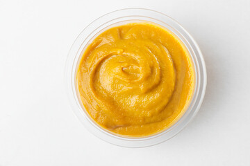 Top view on a cup of liquid mustard on white background