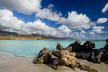 White clouds on blue sky turquise sea water, rocks warm summer feeling